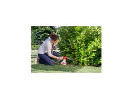 Glückliche Frau beim Gießen und Verteilen von Nematoden auf Blumen mit dem AquaNemix Dossiergerät. Die Pflege der Pflanzen erscheint kinderleicht