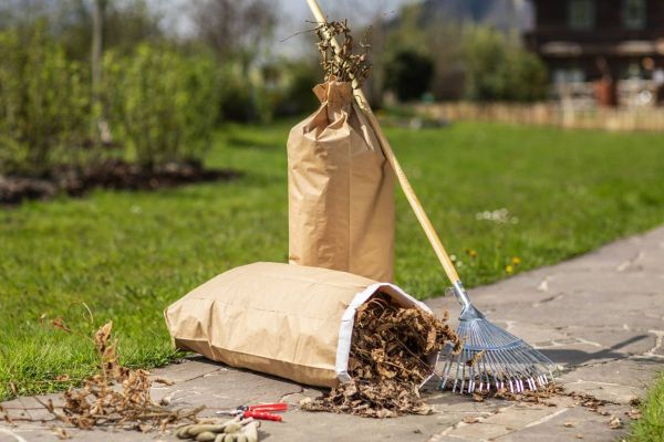 Hände binden einen vollen Papier-Abfallsack zusammen