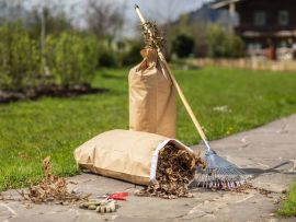 Hände binden einen vollen Papier-Abfallsack zusammen